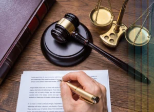 Hand signing legal document near gavel and justice scales shows credibility and legal presence